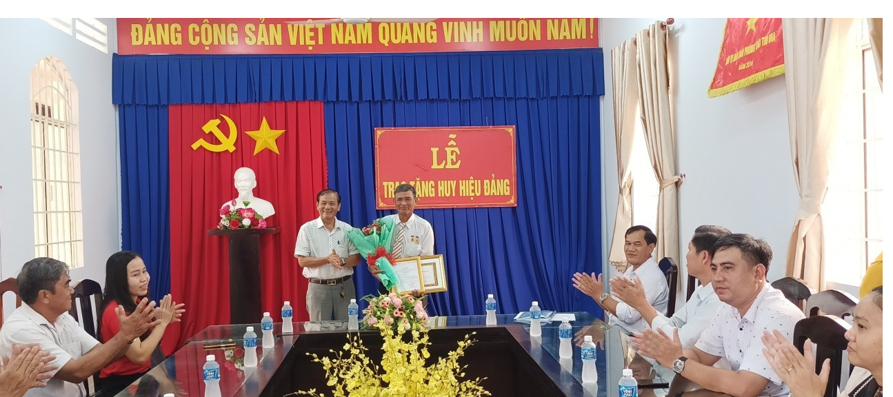 Đồng chí Lê Hồng Vân – Thị uỷ viên, Chủ tịch UBND Thị xã (bên trái) trao tặng Huy hiệu Đảng cho đảng viên Trần Văn Tâm